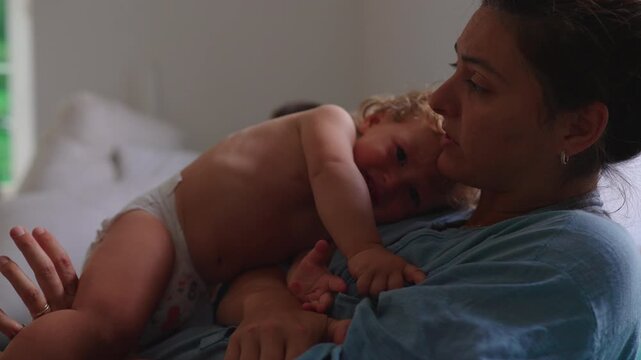 Tired toddler resting on mother&rsquo;s chest during quiet family moment capturing comfort, attachment and authentic emotional bonding at home