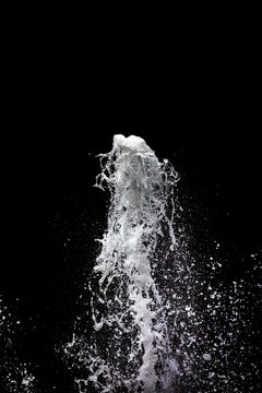 Water fountain shooting into the air with a black background, with copy space