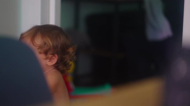 Toddler holding scooter handlebars while learning balance indoors capturing early mobility, coordination and authentic everyday childhood development