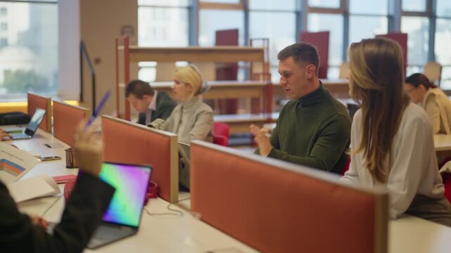 Young professionals are engaged in a discussion while working in a modern office environment. They are collaborating and exchanging ideas in a productive workplace setting.