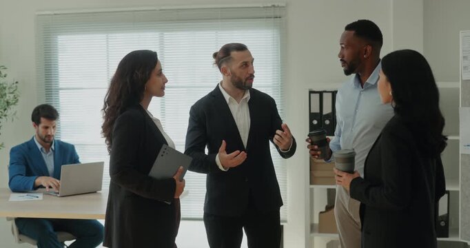 Portrait of serious Middle Eastern leader communicates with multiracial team in office. Arab corporate manager presents workflow to coworkers in workplace