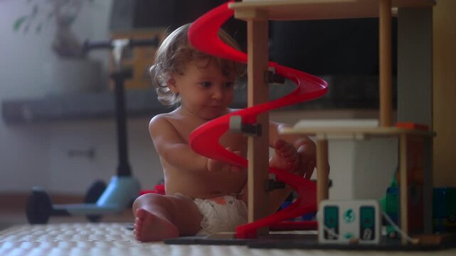 Toddler playing with toy parking garage on play mat during morning at home in sunlit living room focusing on curiosity and cognitive development