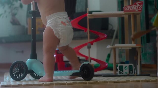 Toddler pushing and riding scooter indoors during playful home activity capturing childhood independence, motor skill development and authentic family lifestyle