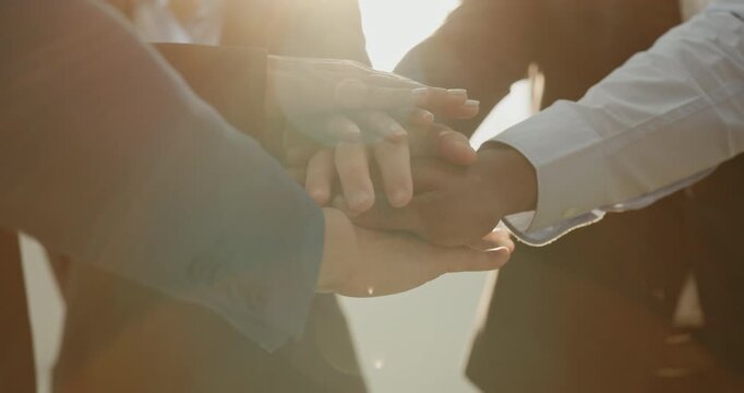 Crop view of international business partners stack hands as trust and connectivity in office. Entrepreneurs show cooperation at teambuilding session indoors