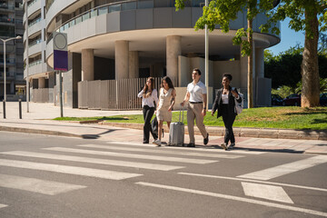 Diverse friends traveling across city crosswalk with luggage © Miljan Živković