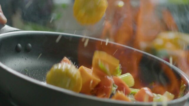 Chef Tossing Mixed Vegetables in Frying Pan with Flambe Fire