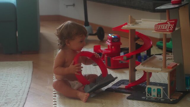 Young child holding toy car while sitting near a wooden play structure in a bright room representing curiosity and the concept of early educational engagement