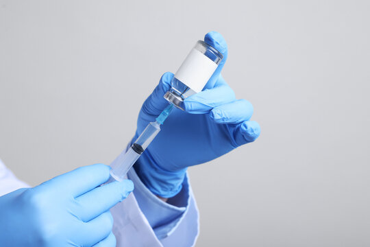 Vaccination. Medical worker filling syringe with medication on light grey background, closeup. Space for text