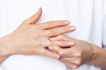 Fototapeta premium Woman struggles to remove a ring stuck on her finger, showing tension and effort in her hands moment in close-up detail. 