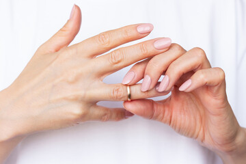Fototapeta premium Woman in white clothes putting a wedding ring on her ring finger.