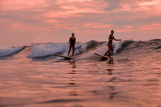 Two Surfers Sharing Sunset Swell, Matching Pace And Friendly Exchange, Mutual Support, Warm Orange Sky,