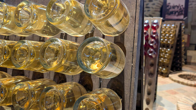 Wine bottles resting on their sides within wooden racks as part of the riddling process, developing character and flavor in a cool, dark cellar environment at a vineyard estate