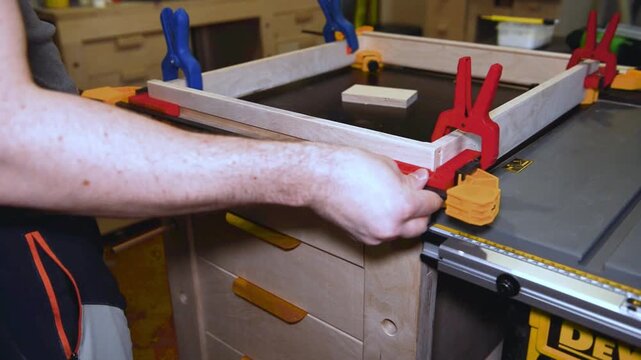 Set of clamps tools instruments for compressing and gluing wooden beams on work table in carpentry workshop, small business woodshop creating handmade items and furniture for home and living.