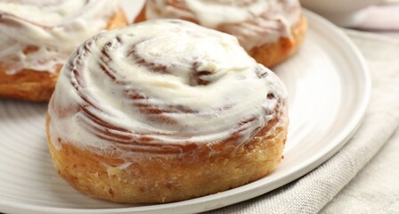 Fototapeta premium Tasty cinnamon rolls with cream on table, closeup