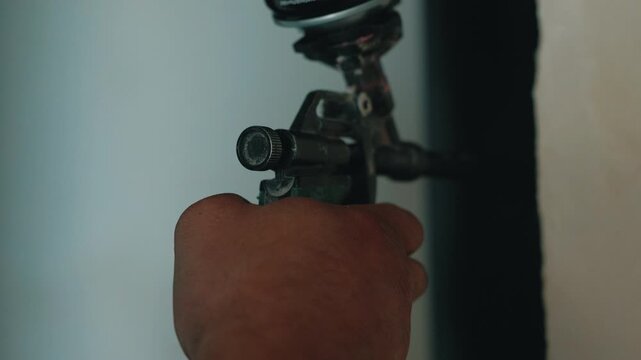 Worker applying polyurethane foam with spray gun during installation