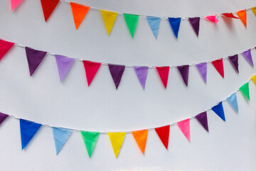 Obraz premium Colorful bunting flags on white wall for party celebration. Background with copy space