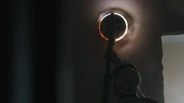 Worker polishing interior wall with illuminated drywall sanding machine