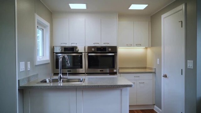 Modern Luxury Kitchen Interior with white cabinets stainless steel appliances and island sink smooth panning shot
