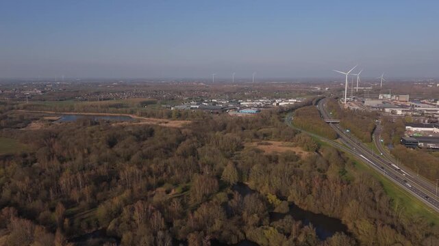 Reverse wide aerial view of wind turbines and industrial port