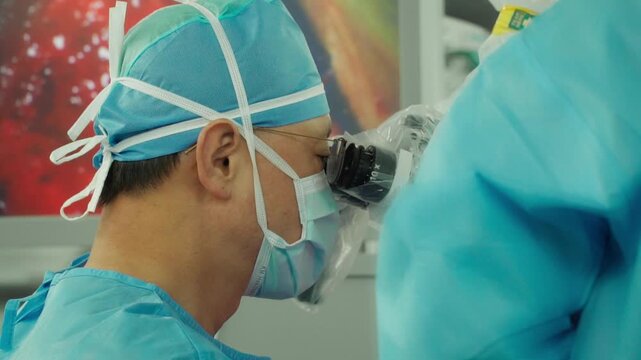 A medical professional performs a delicate brain neurosurgery procedure using an operating microscope in a surgical room surrounded by advanced monitoring