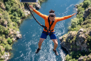 Naklejka premium Adventurer bungee jumping from bridge over canyon and river
