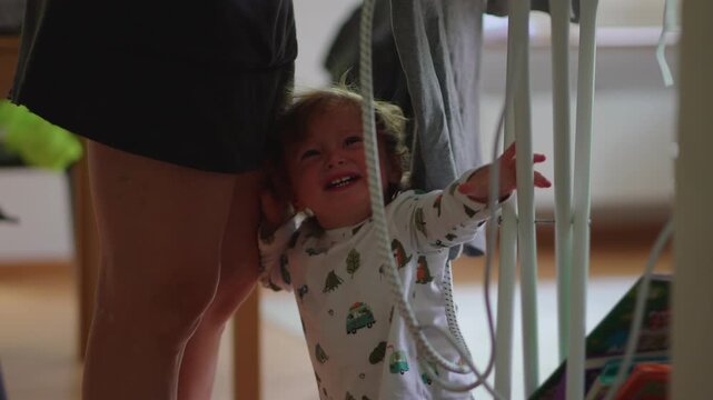 Crying toddler seeking attention from woman ironing clothes in home interior capturing emotional parenting challenges, attachment and authentic family life