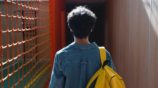 Back view student guy in school teenager with schoolbag walking in sport hall unrecognizable Caucasian boy pupil male man teen schoolboy backpack university college walk go physical education studying