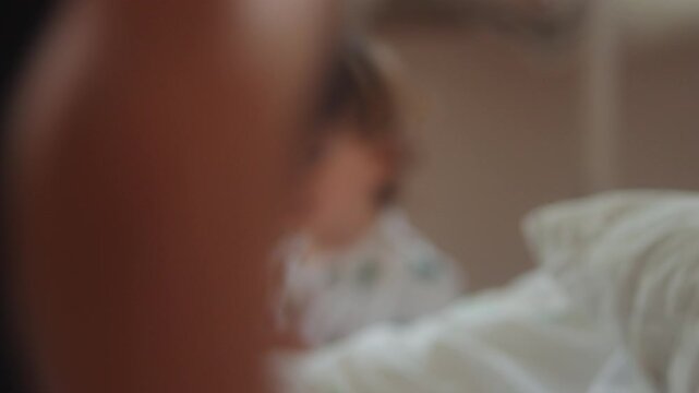 Curious toddler watching sibling move across bed during quiet family moment capturing childhood observation, discovery and authentic early learning experience