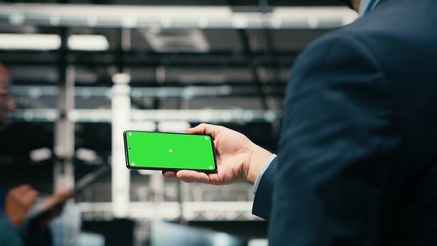 Green screen smartphone, managing blue wireframe mesh gear and admin in data center helping power internet services, Using mockup phone, digital storage systems and worker in server farm, camera B.