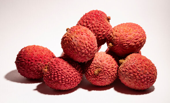 Lychee, (Litchi chinensis),  is a monotypic taxon and the sole member in the genus Litchi in the soapberry family, Sapindaceae. A pile of berries on a white background.