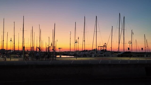Senigallia pier and sail boats shilouettes at sunset, with beautiful orange sky. - Marche region, Italy