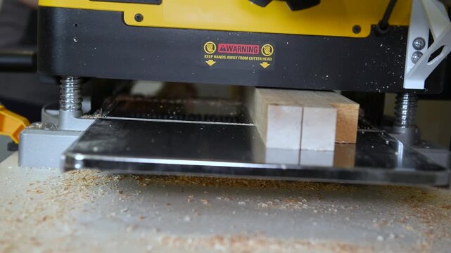 A wood plate passing through the thickness planer machine in a carpentry workshop. Woodworking process, furniture preparation, handmade craftsmanship, carpentry studio.