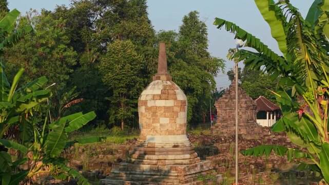 Aerial view of Plaosan Kidul Temple featuring ancient stone stupas surrounded by lush tropical greenery and banana trees in Kecamatan Prambanan, Jawa Tengah, Indonesia.