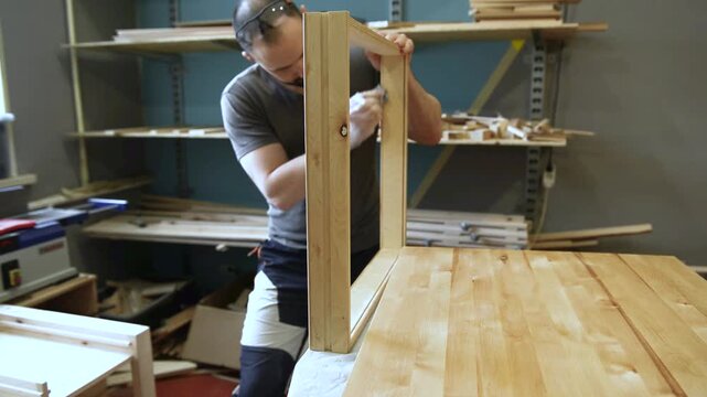 Master carpenter, Applying natural oil on natural wood product. A joiner applies a wood impregnation to a wood product. Carpenter applying protective varnish to wooden surface in workshop