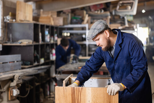 Experienced furniture assembler assembles wooden table at furniture factory