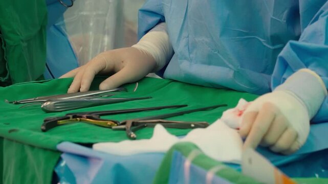 Surgical clamps and medical equipment on green surgical tray inside operating room.