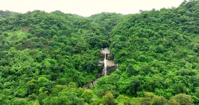 Aerial view of a multi-tiered waterfall cascading down a steep hillside covered in dense tropical vegetation and lush green trees Meghalaya, India.