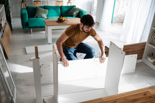 Young man assembling diy flat pack furniture in living room