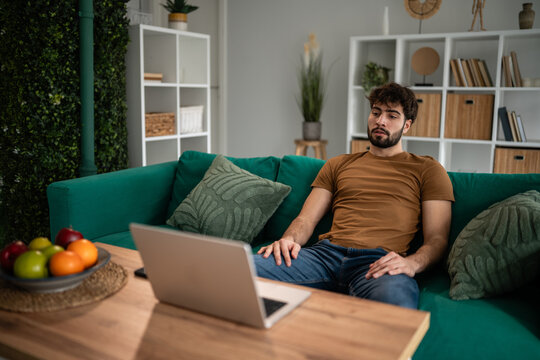 Man relaxing on sofa using laptop for remote work