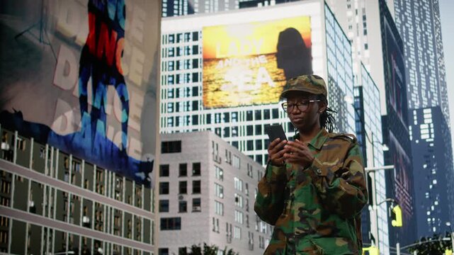 Army soldier examines smartphone map app and walking on city street, metropolitan area downtown. Black military officer using phone navigation to check tactical route coordinates, city center.
