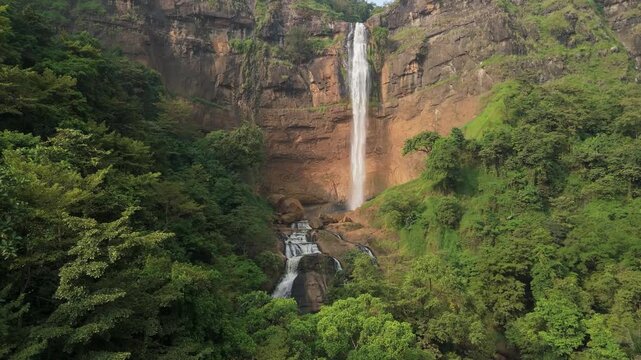 Aerial view of Cikanteh Waterfall cascading down a rocky cliff surrounded by dense tropical forest and lush green trees in Sukabumi, West Java, Indonesia.