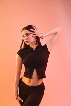 Young hip-hop dancer in stylish clothes posing on color background