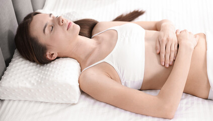 Obraz premium Woman sleeping on bed with orthopedic pillow at home