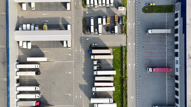 Aerial view of logistics warehouse with trucks parked in designated areas, showcasing organized loading zones and efficient space utilization in a commercial transport facility