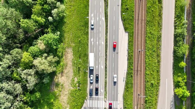 Aerial view of busy intersection with vehicles navigating roads, surrounded by greenery, showcasing traffic flow and road configurations in a vibrant urban environment