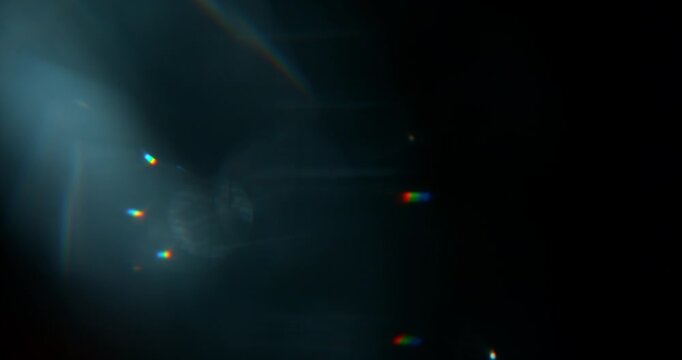Super slow motion blue lens flare moving across black background. Cinematic optical overlay with rainbow reflections and glowing streaks for VFX compositing effects.
