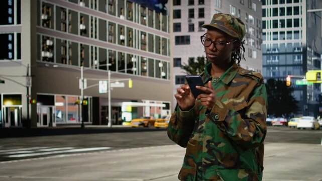 Delighted army soldier outdoors gasping after receiving good news on phone, returning home and feeling happy. Thrilled woman on city street surprised by message on smartphone.