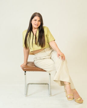 Confident Woman Sitting on Chair on White Background