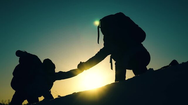 Business team victory. Free people strive victory. Teamwork in travel. Tourists climb mountain together. Teamwork business. Achieve your goal. Climbers holding hands, climb to top of hill. Silhouettes