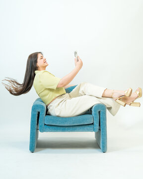 Woman Relaxing on Chair Using Smartphone on White Background